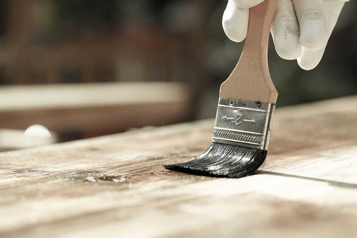 Hand mit Pinsel streicht Holz ein